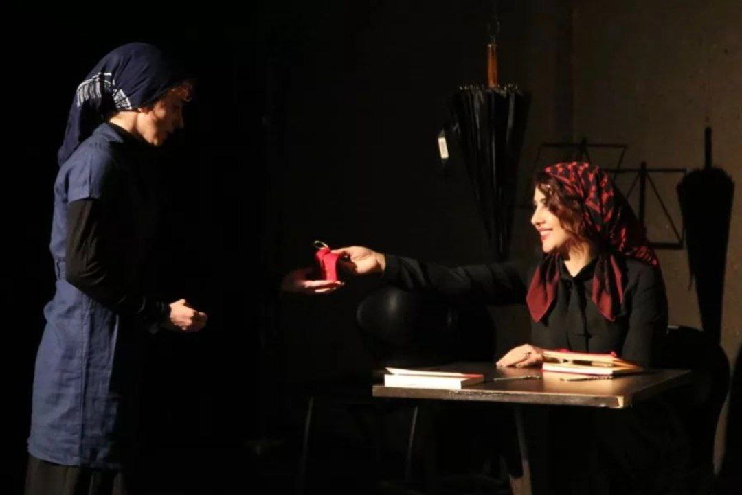 Actors seated across a table on stage